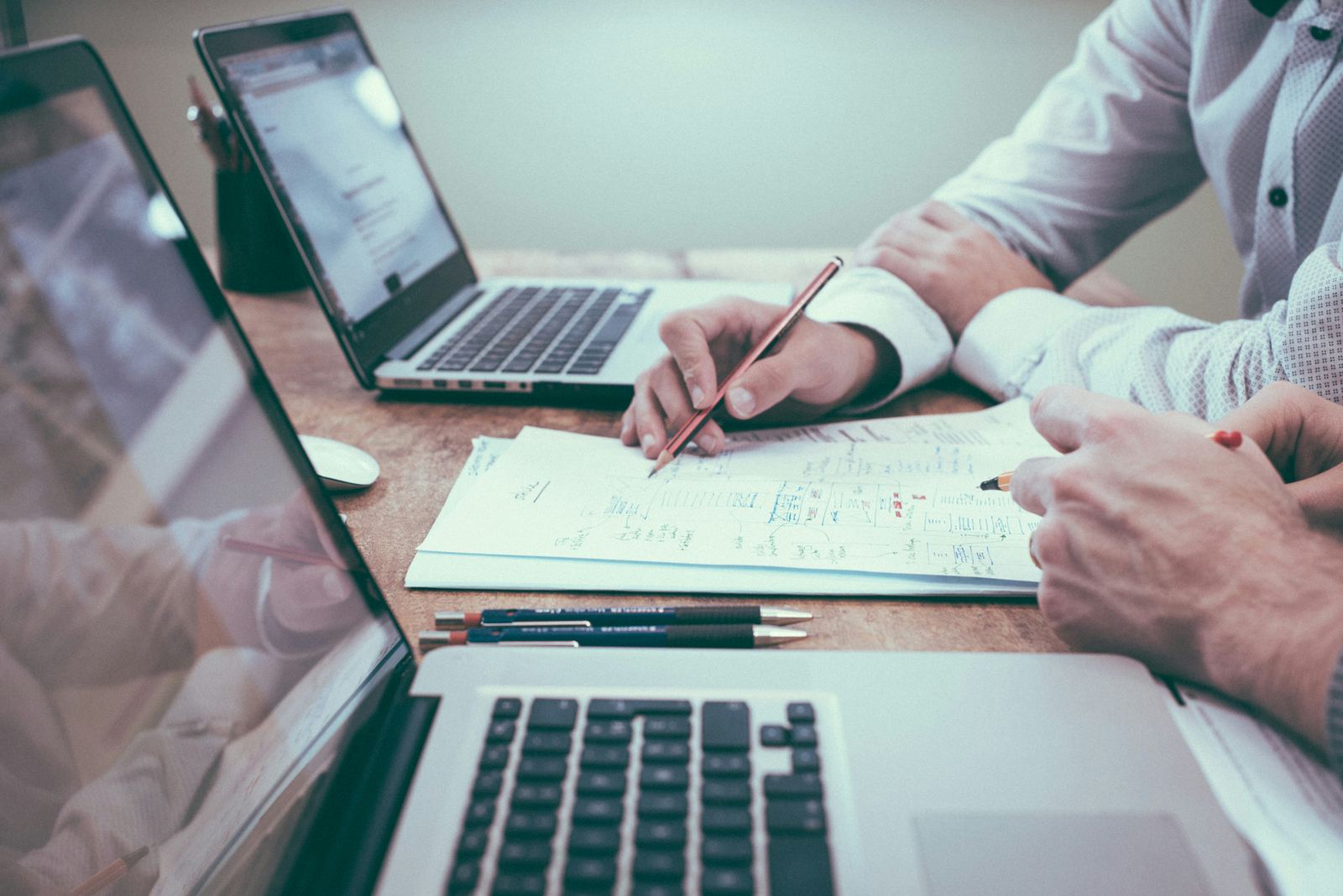 Due professionisti al tavolo con computer portatili, matite e appunti